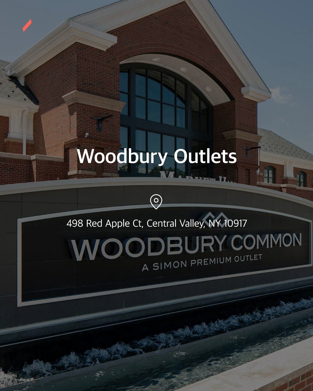 브릭 건물 외벽에 Woodbury Outlets 간판이 설치된 상업 시설의 모습