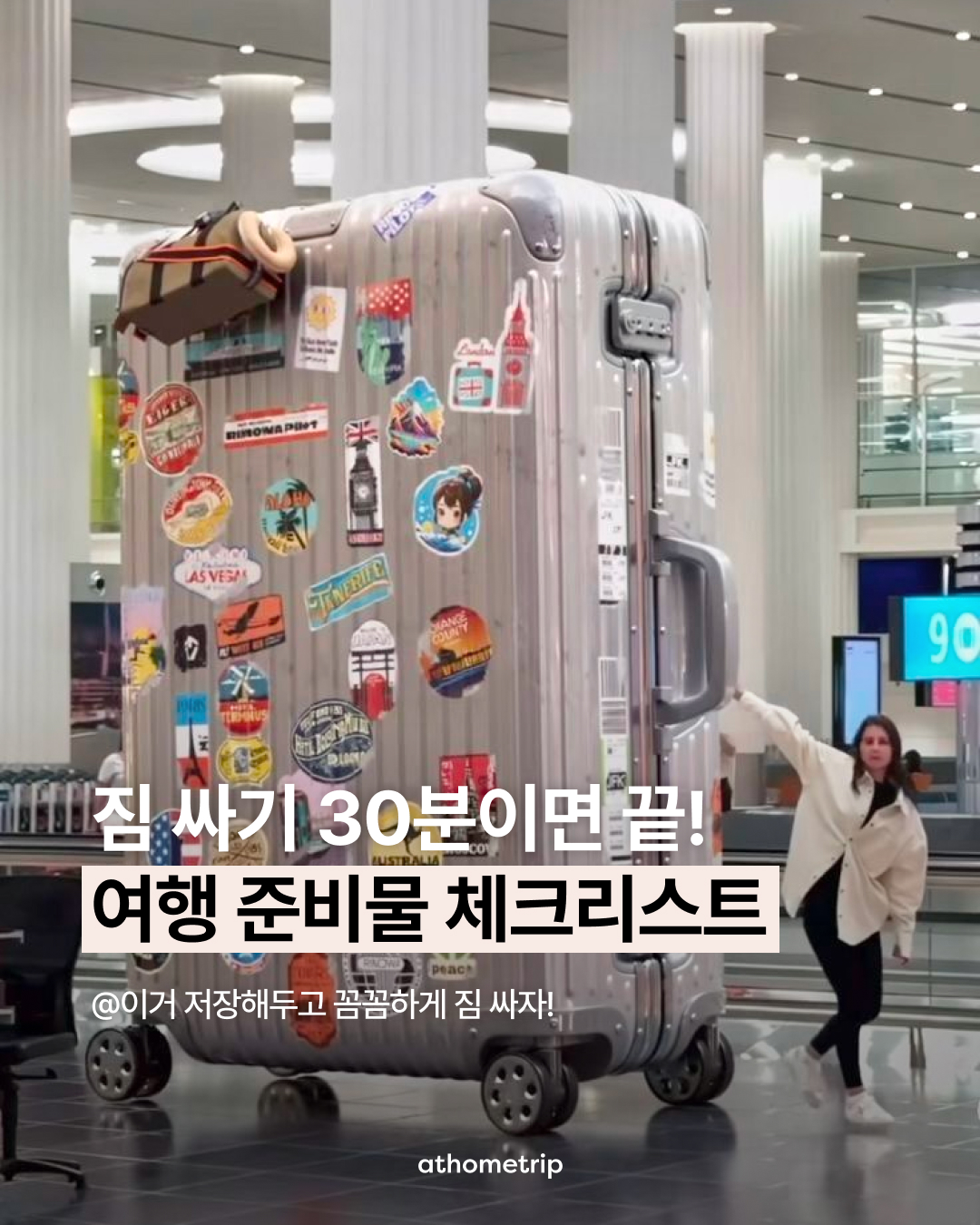 공항 내부 기둥 옆에 스티커가 붙은 큰 여행 가방이 놓여 있는 모습