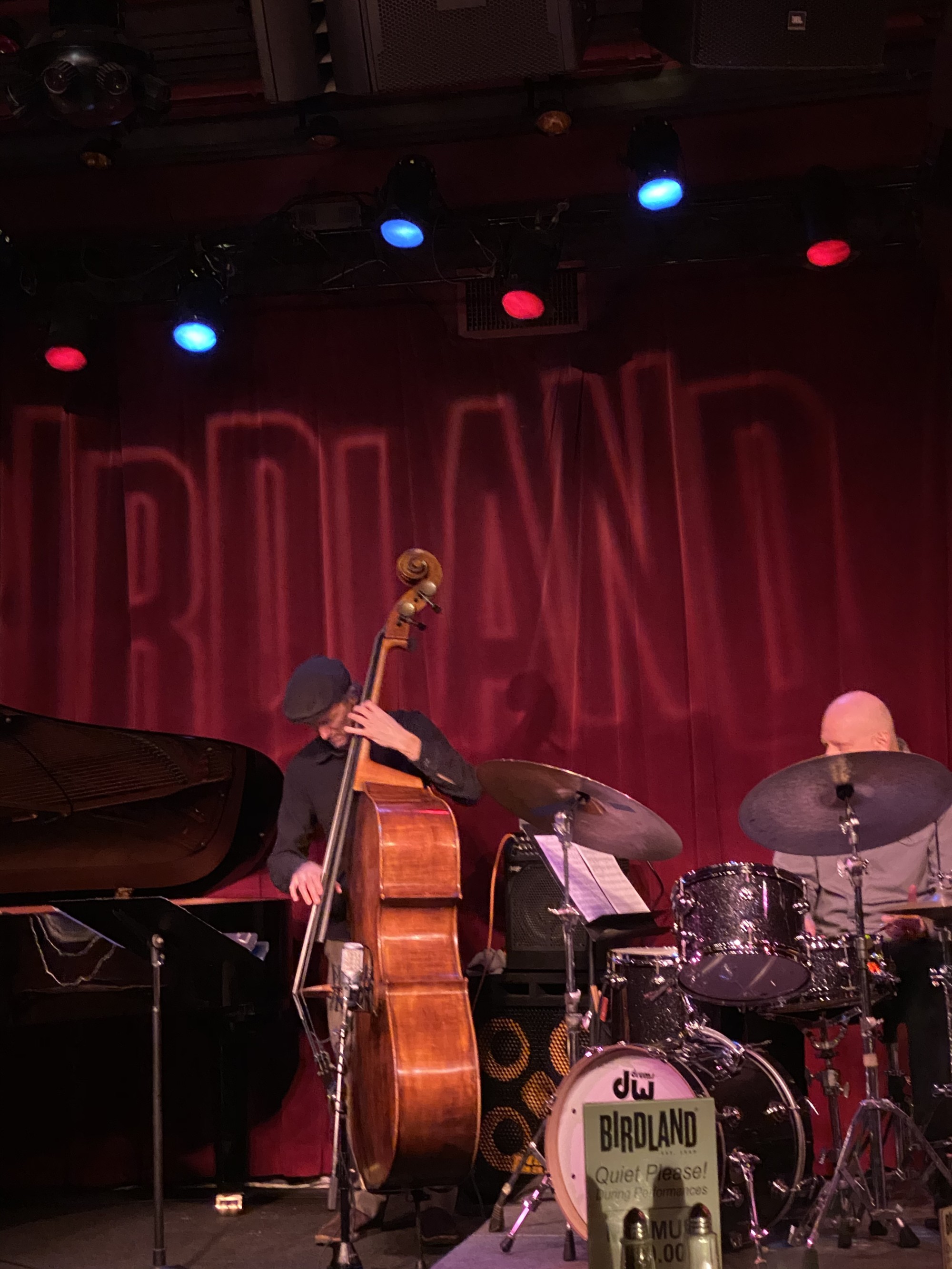 BIRDLAND 무대 위 피아노, 베이스 기타, 드럼 세트가 있는 공연 장면