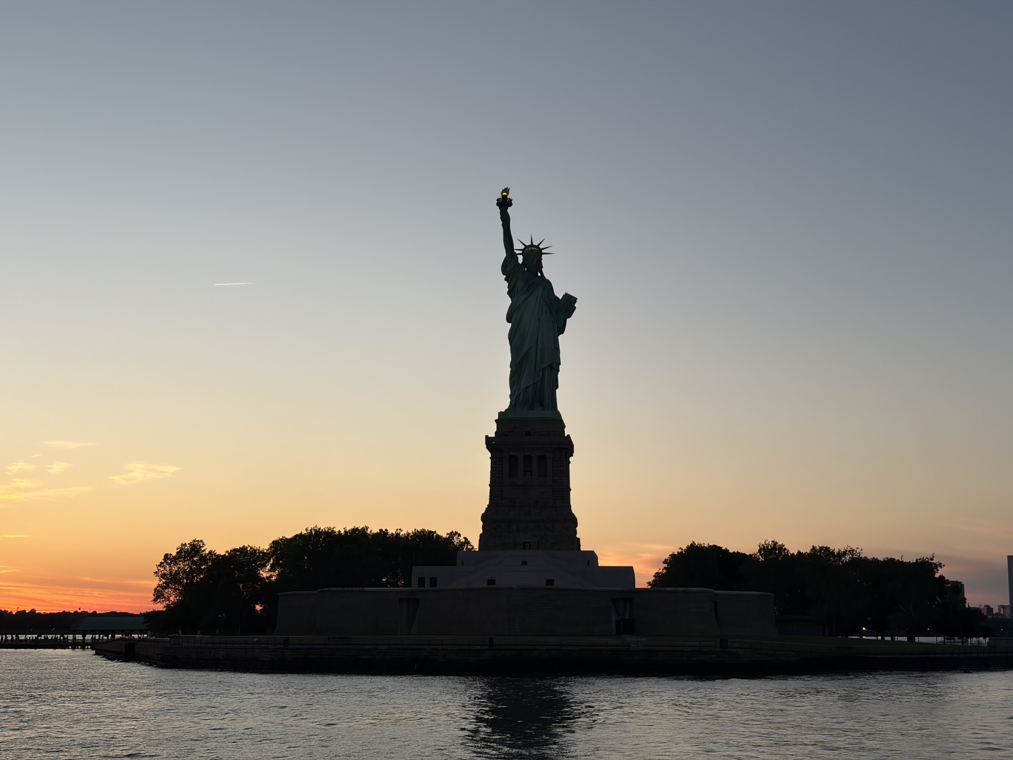 조각상과 나무가 보이는 실외 풍경에 하늘과 물이 어우러진 장면