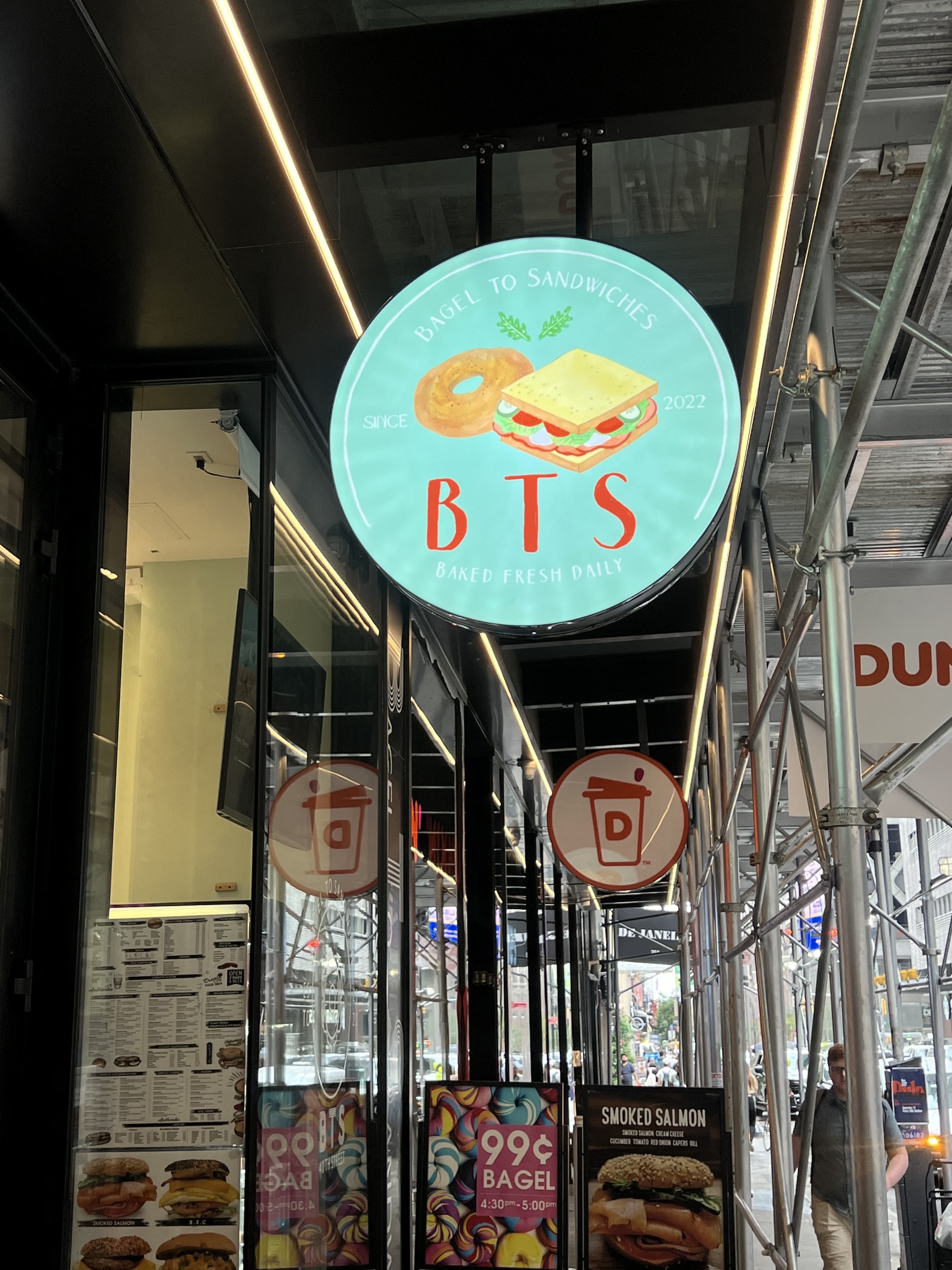 도시 거리의 건물 유리창과 BTS라고 적힌 간판이 보이는 실외 풍경