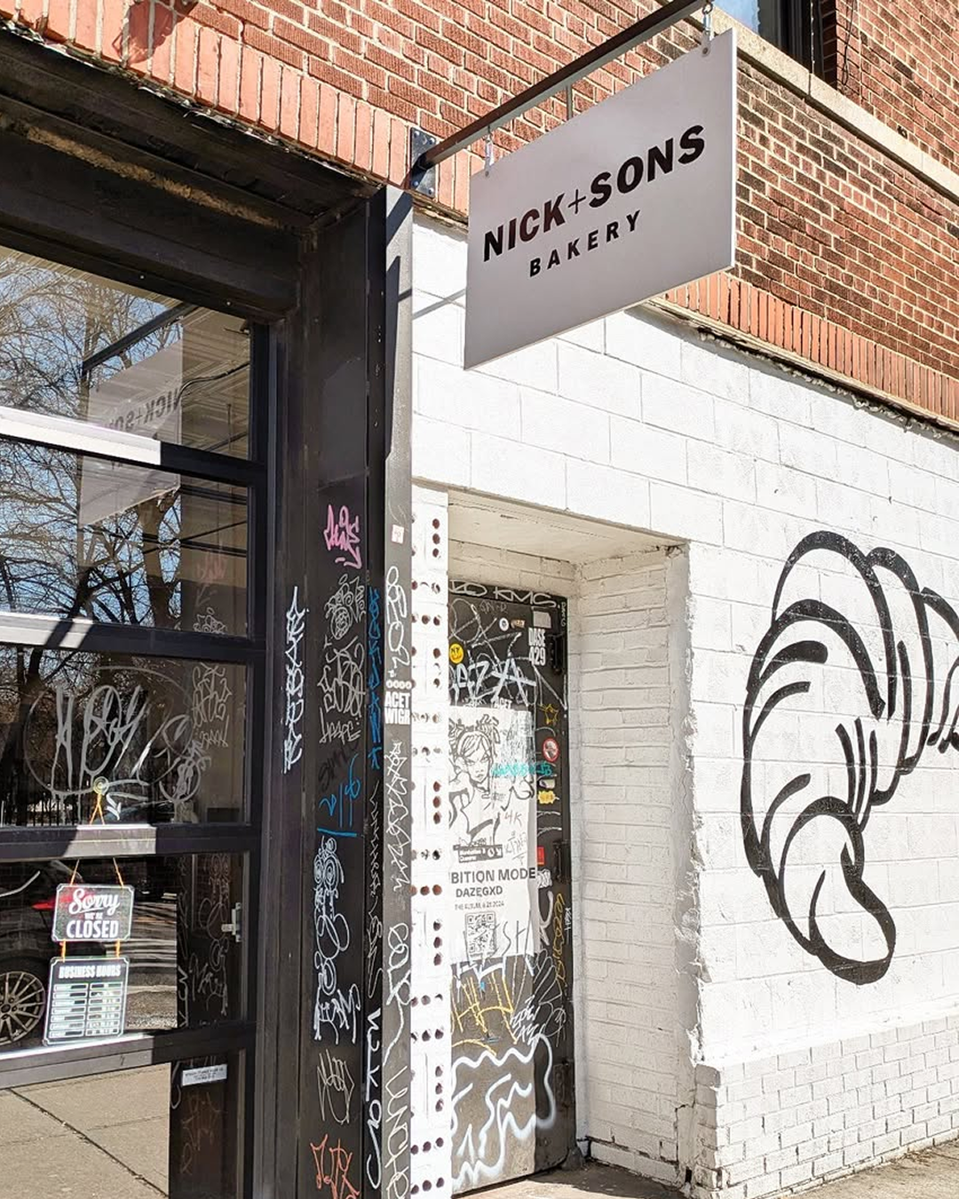 NICK+SONS BAKERY라는 문구가 적힌 유리문이 있는 벽돌 건물 베이커리 상점의 외부 모습