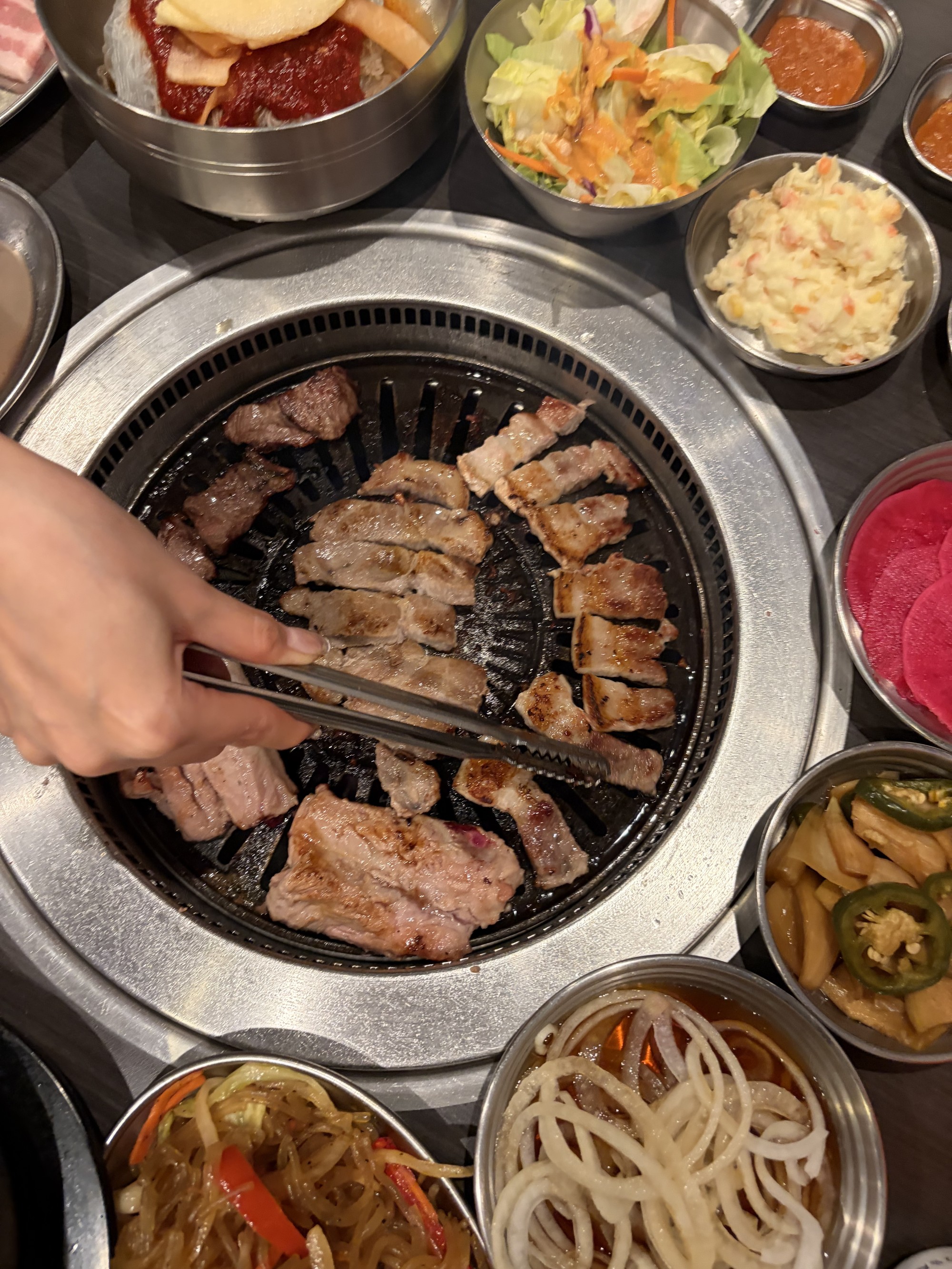 식탁 위에 놓인 구이용 그릴과 고기, 여러 종류의 반침이 차려진 모습