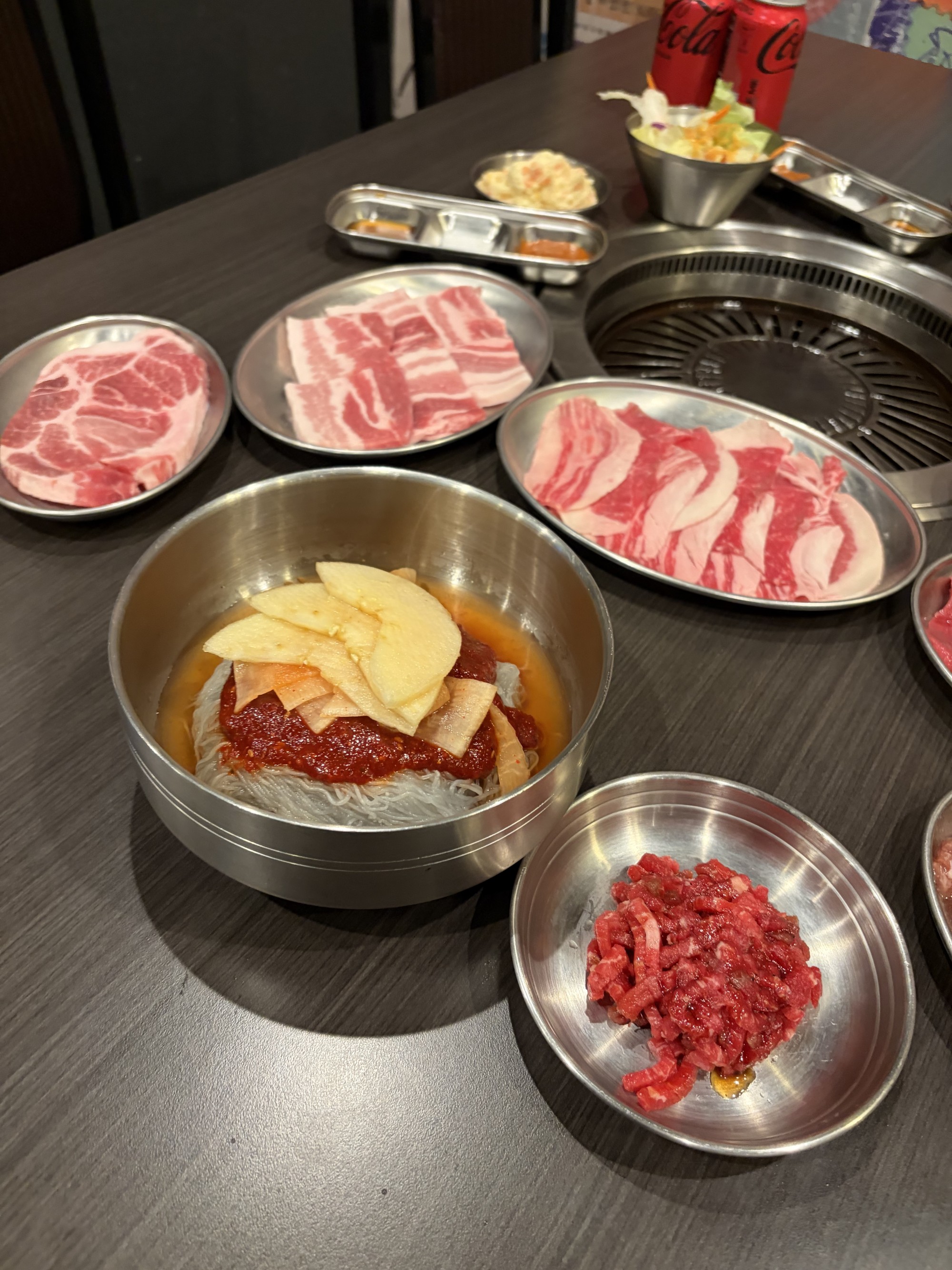 식탁 위에 고기, 야채, 소스가 담긴 접시가 놓여 있는 모습