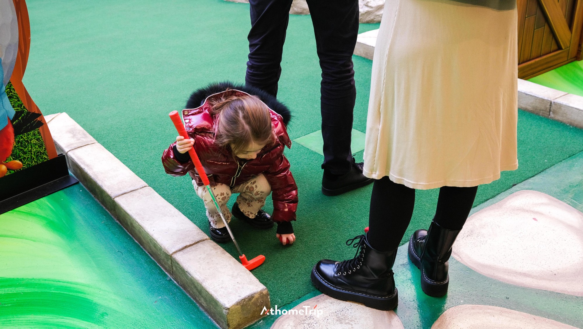 실내에서 아이와 사람이 골프 클럽을 사용하는 모습