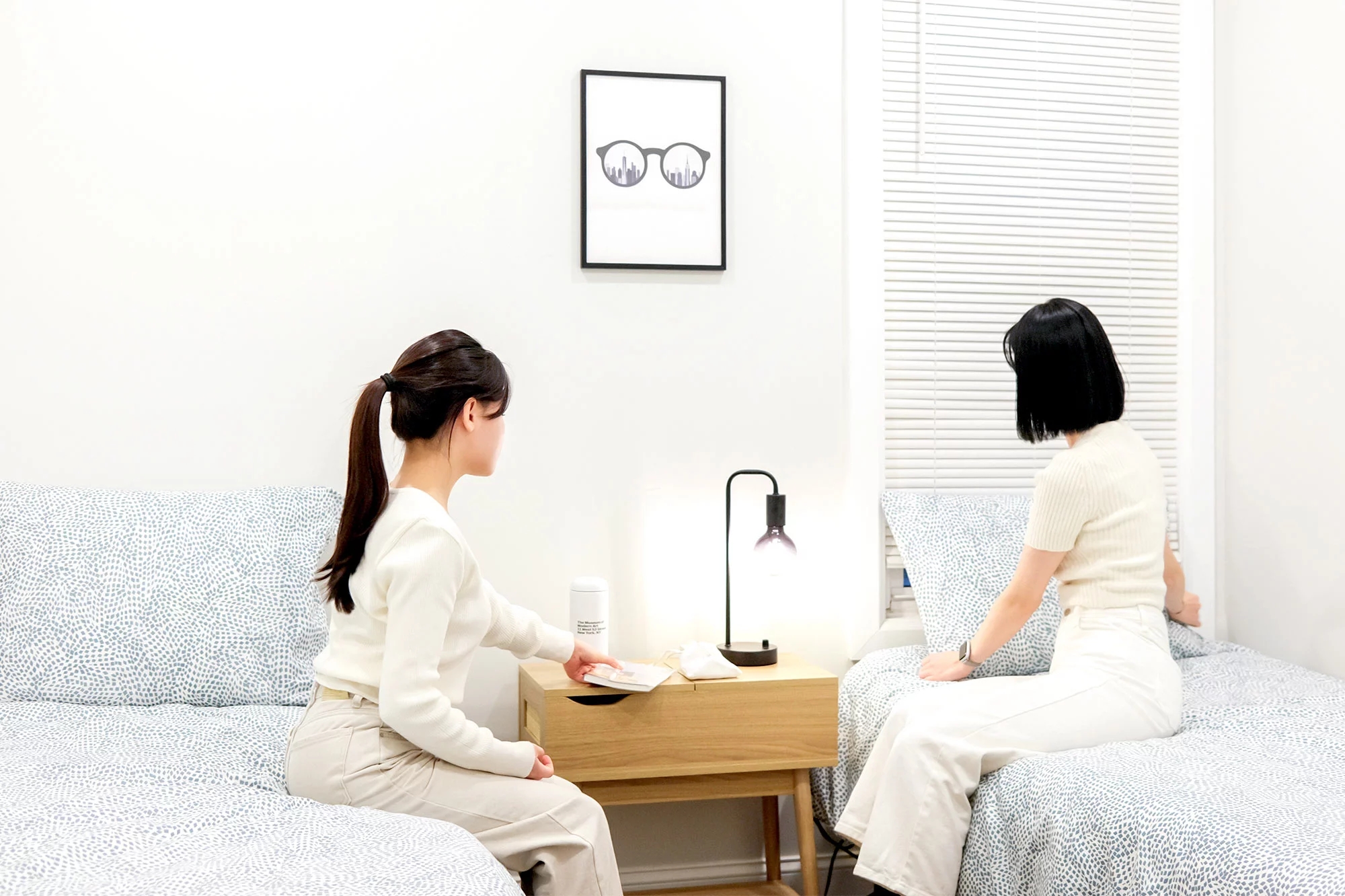 실내에서 두 사람이 소파와 침대에 앉아 탁자 위의 물건을 보는 모습