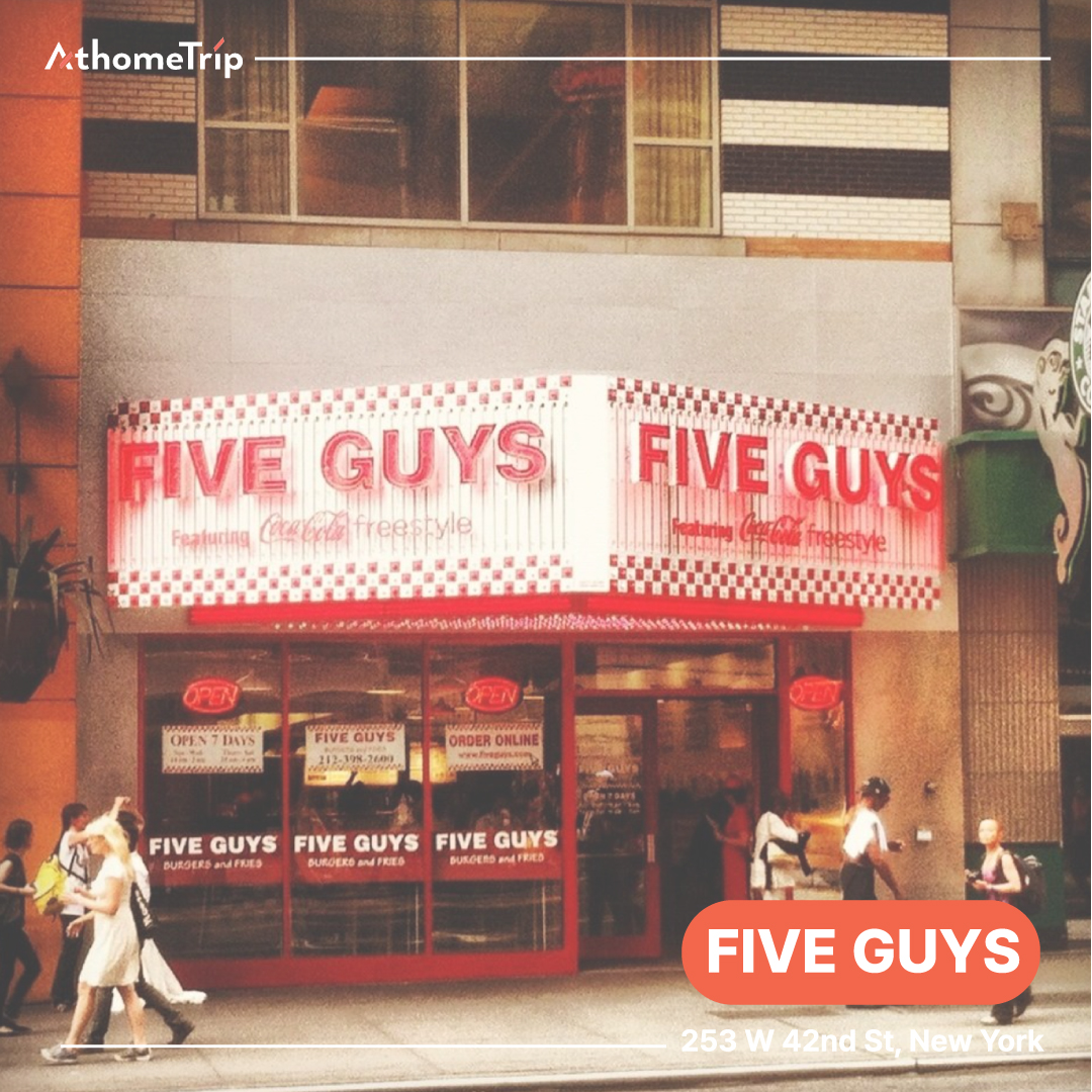 도시 거리의 건물 외벽에 FIVE GUYS라는 간판이 붙어 있는 식당 모습
