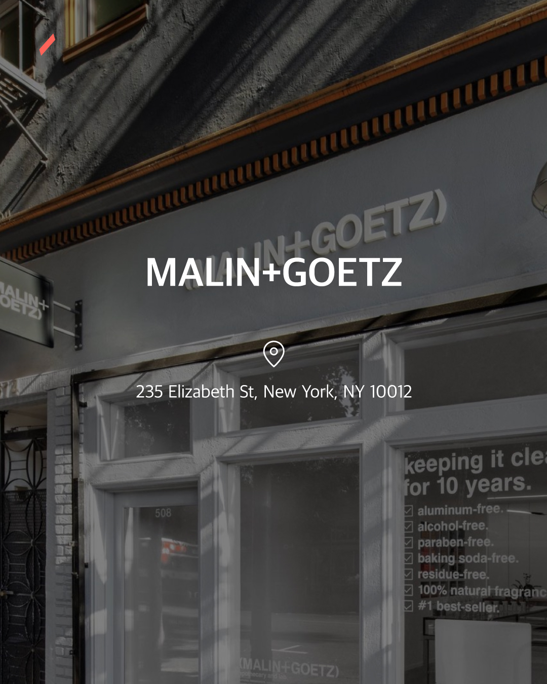 MALIN+GOETZ 문구가 적힌 간판과 건물의 유리창이 보이는 도시 장면