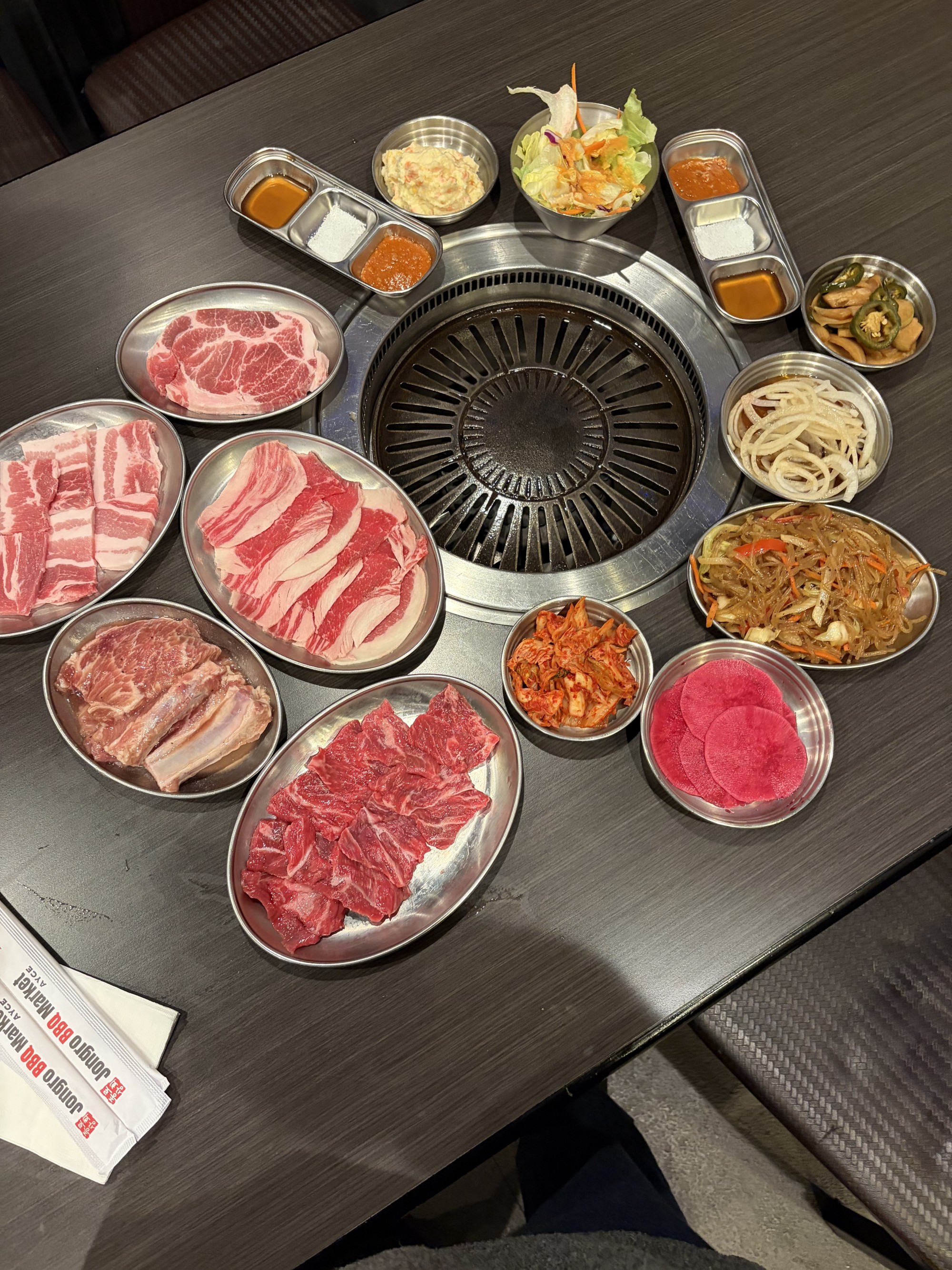 테이블 위에 여러 종류의 고기와 채소, 소스가 담긴 접시가 놓여 있는 사진