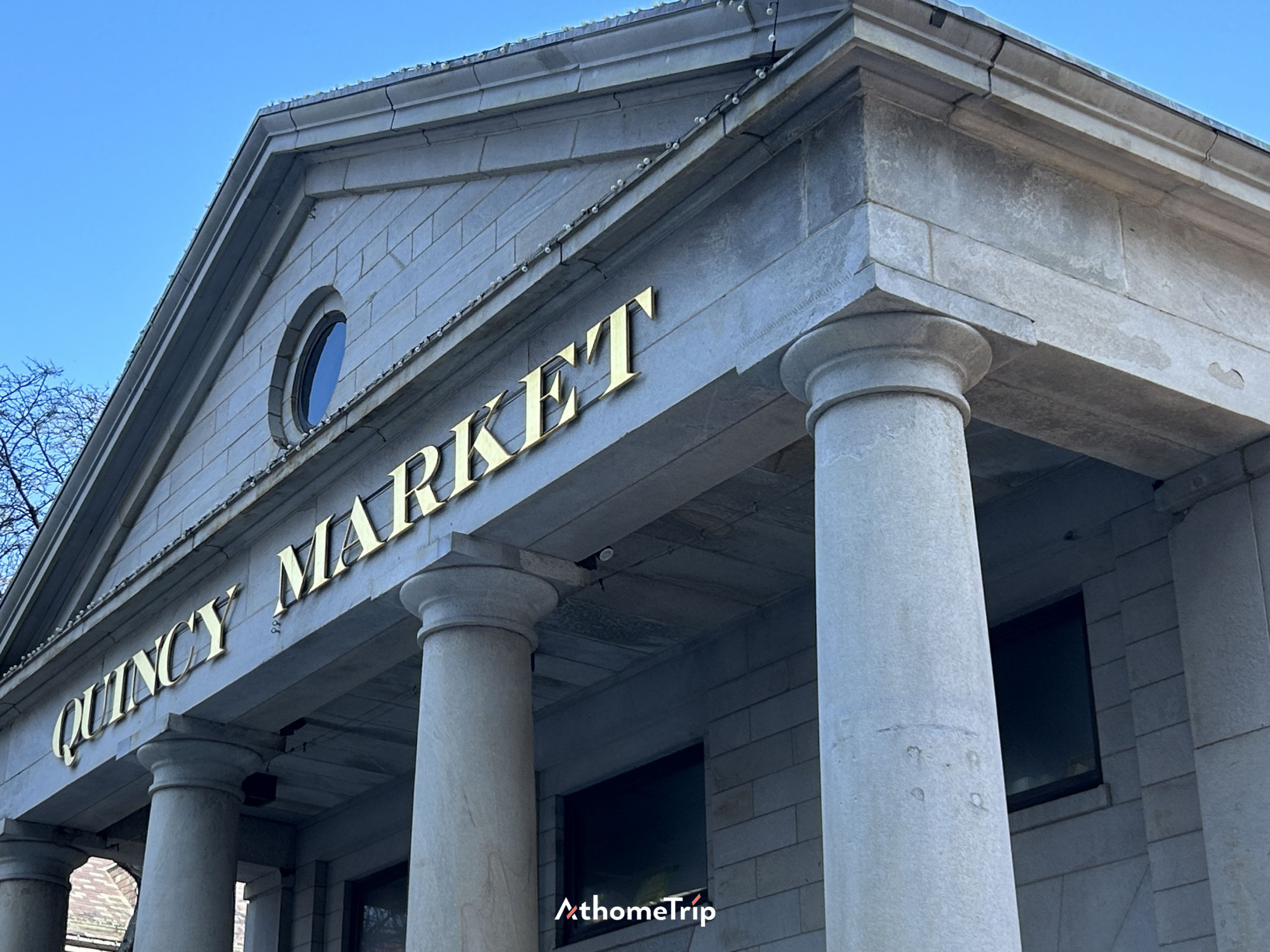 QUINCY MARKET 문구가 적힌 간판과 건물의 기둥이 보이는 실외 모습
